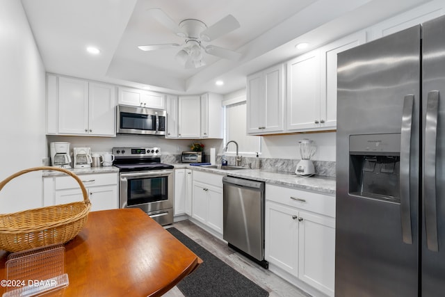 kitchen featuring white cabinets, appliances with stainless steel finishes, sink, and a tray ceiling