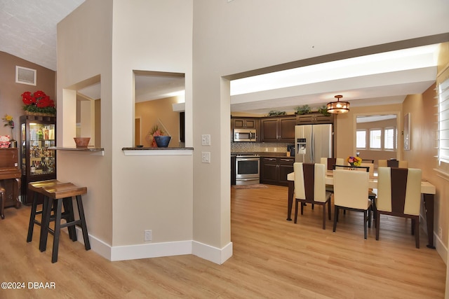 dining room with lofted ceiling and light hardwood / wood-style floors