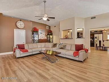 living room featuring vaulted ceiling, ceiling fan, and light hardwood / wood-style floors