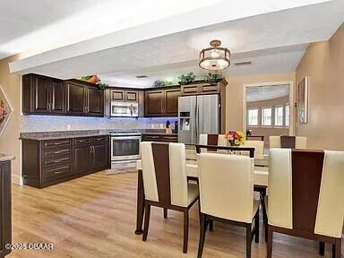 kitchen featuring light wood-type flooring, dark brown cabinets, and appliances with stainless steel finishes