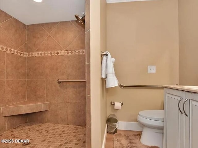 bathroom featuring vanity, a tile shower, and toilet