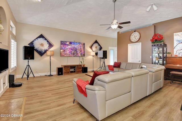 living room featuring a textured ceiling, ceiling fan, and light wood-type flooring