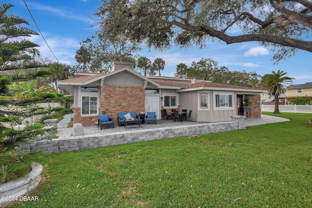 rear view of property with outdoor lounge area, a patio area, and a lawn