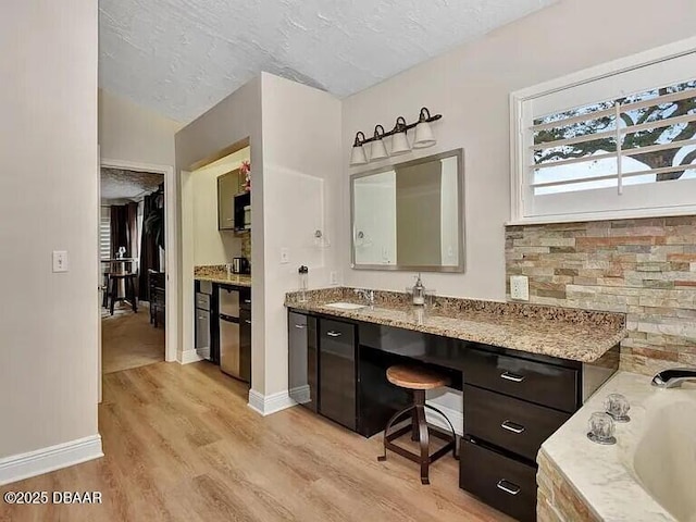 bathroom with vanity, hardwood / wood-style flooring, a tub, and a textured ceiling