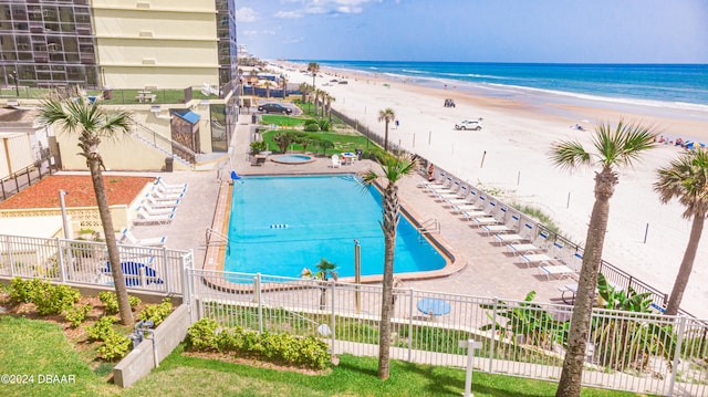 view of swimming pool with a patio area, a view of the beach, and a water view