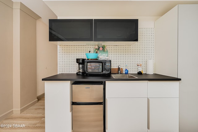 kitchen featuring light hardwood / wood-style floors, stainless steel refrigerator, white cabinetry, and sink