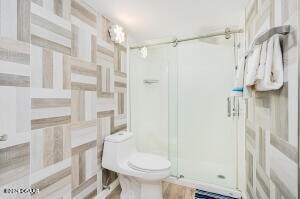 bathroom featuring toilet and a shower with shower door