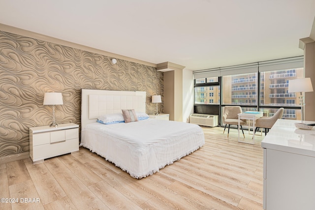 bedroom with a wall of windows and light hardwood / wood-style flooring