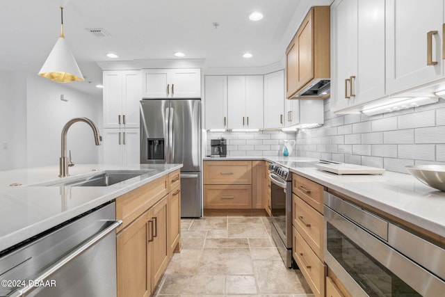 kitchen featuring stainless steel appliances, pendant lighting, decorative backsplash, light stone countertops, and white cabinetry