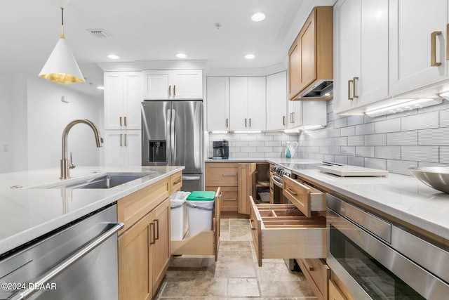 kitchen with tasteful backsplash, white cabinetry, appliances with stainless steel finishes, pendant lighting, and sink