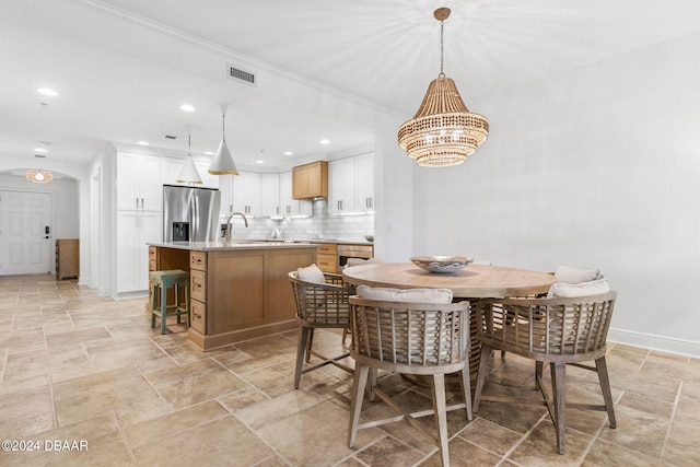 dining space with sink, crown molding, and an inviting chandelier