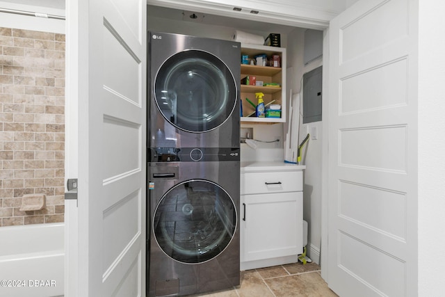 washroom with stacked washer and clothes dryer, cabinets, and light tile patterned floors