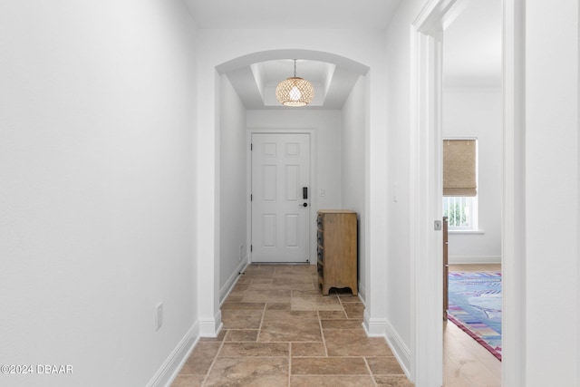 146 Palm Coast Resort Blvd Unit 409, Palm Coast, FL 32137 - hallway featuring arched walkways, baseboards, light stone finish flooring, and a tray ceiling
