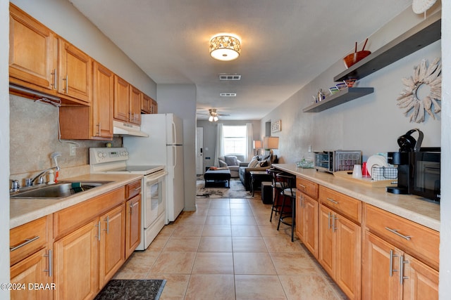 kitchen featuring a kitchen bar, white range with electric cooktop, sink, light tile patterned floors, and ceiling fan