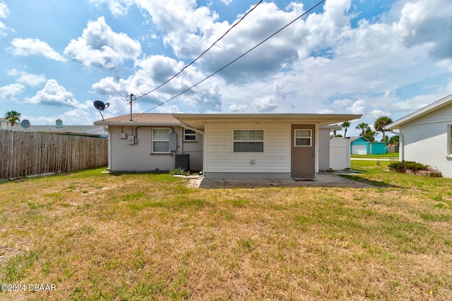 rear view of house with central air condition unit and a lawn