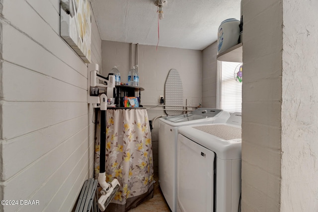 clothes washing area featuring a textured ceiling and washing machine and clothes dryer