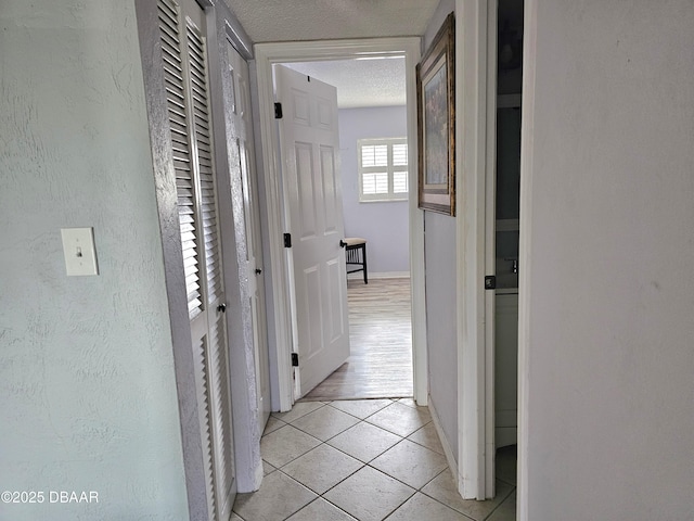 hallway with light tile patterned floors and a textured ceiling