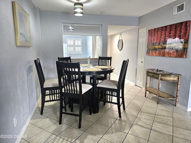 dining space with a textured ceiling and light tile patterned floors