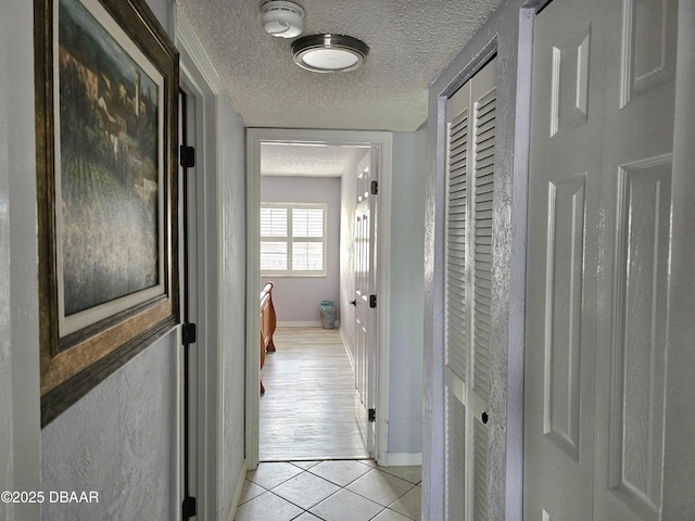 hallway with light tile patterned floors and a textured ceiling