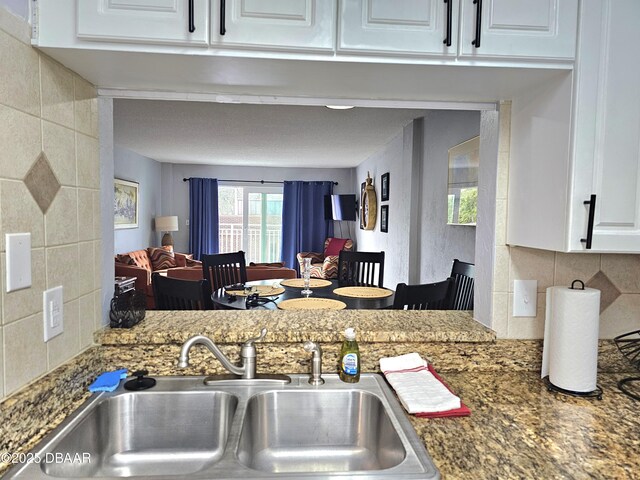 kitchen with stone countertops, sink, white cabinets, and decorative backsplash