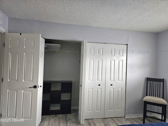 bedroom featuring two closets, light hardwood / wood-style floors, and a textured ceiling