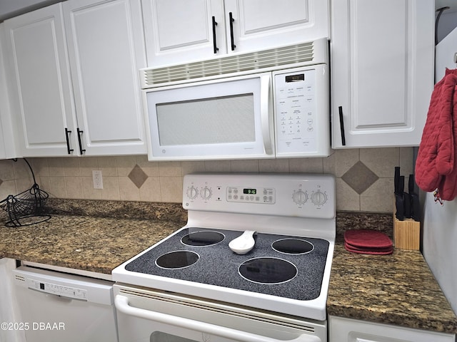 kitchen with dark stone countertops, backsplash, white appliances, and white cabinets