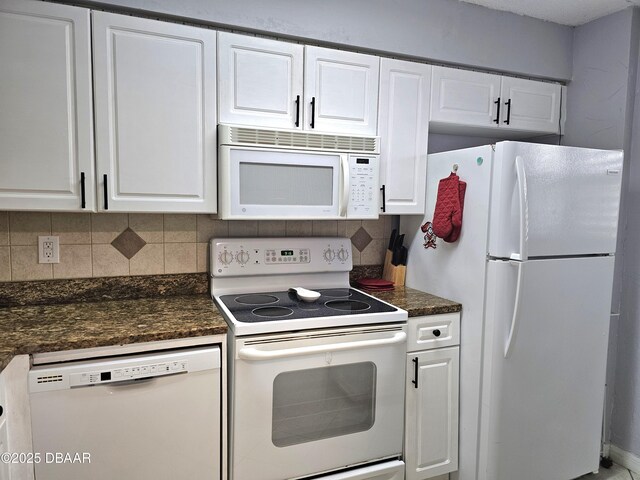 kitchen with white cabinetry, white appliances, dark stone counters, and backsplash