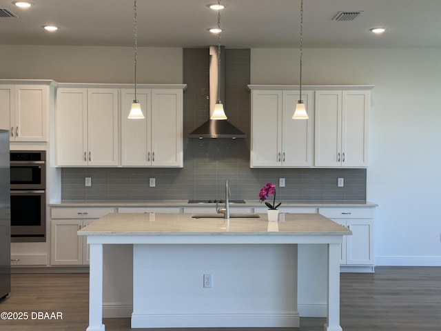 2009 Divot Dr, Daytona Beach, FL 32124 - kitchen featuring dark wood-style floors, decorative backsplash, white cabinetry, and wall chimney exhaust hood