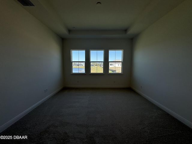 2009 Divot Dr, Daytona Beach, FL 32124 - spare room with baseboards, a raised ceiling, and dark carpet