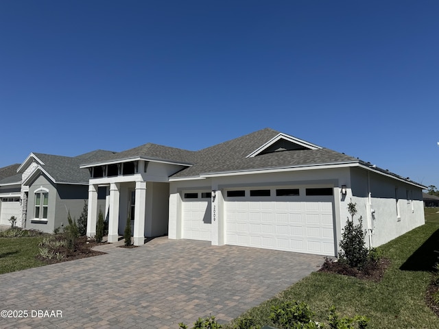 view of front of house with stucco siding, a shingled roof, decorative driveway, and a garage