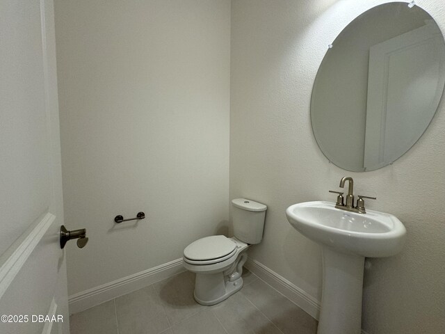 2009 Divot Dr, Daytona Beach, FL 32124 - half bathroom featuring tile patterned floors, baseboards, toilet, and a sink
