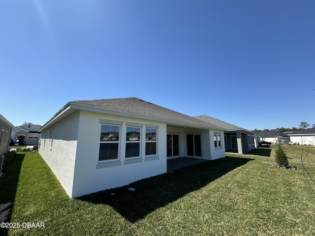 2009 Divot Dr, Daytona Beach, FL 32124 - rear view of house featuring stucco siding, a lawn, and roof with shingles
