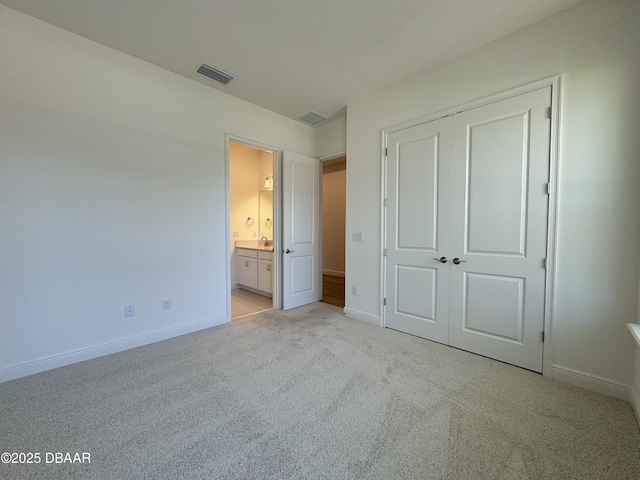 2009 Divot Dr, Daytona Beach, FL 32124 - unfurnished bedroom with visible vents, baseboards, light carpet, a closet, and ensuite bath