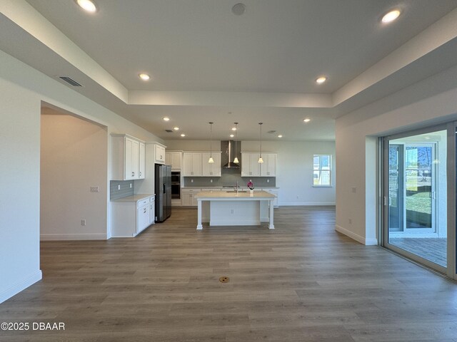 2009 Divot Dr, Daytona Beach, FL 32124 - kitchen with wall chimney range hood, open floor plan, stainless steel refrigerator with ice dispenser, white cabinetry, and a sink