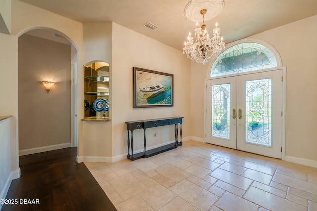 entryway featuring visible vents, baseboards, stone tile floors, french doors, and an inviting chandelier