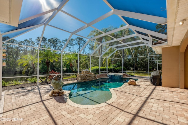 view of swimming pool featuring glass enclosure, a pool with connected hot tub, and a patio