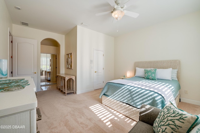 bedroom with light carpet, visible vents, arched walkways, and baseboards