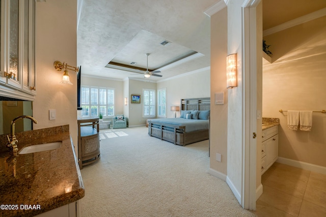 bedroom with visible vents, crown molding, light colored carpet, a raised ceiling, and a sink