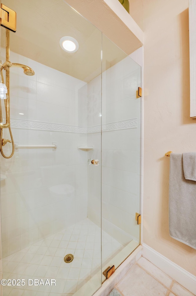 bathroom featuring tile patterned flooring, baseboards, and a stall shower