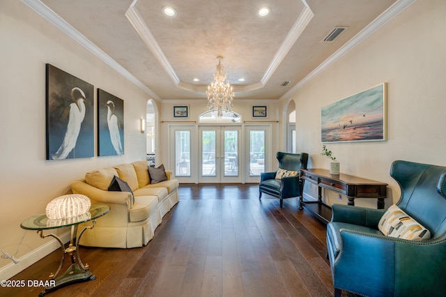 living room with a tray ceiling, visible vents, arched walkways, and dark wood finished floors