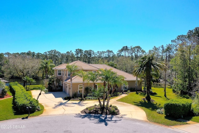 mediterranean / spanish-style home featuring stucco siding, a tiled roof, concrete driveway, and a front yard