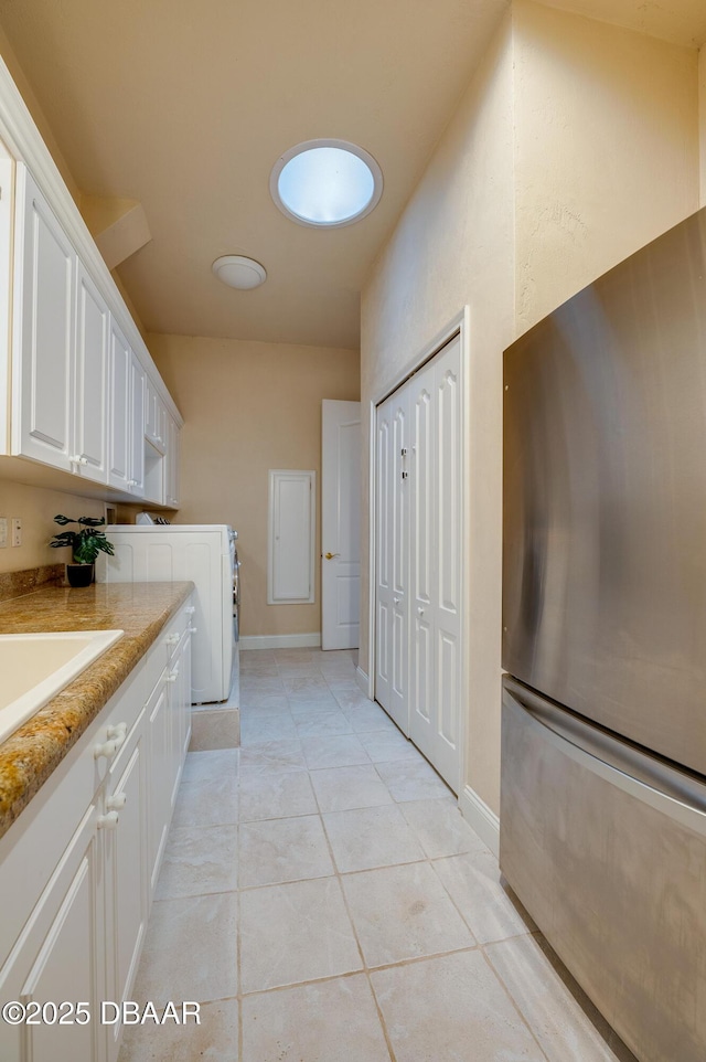 washroom featuring light tile patterned flooring, laundry area, washer / clothes dryer, and baseboards