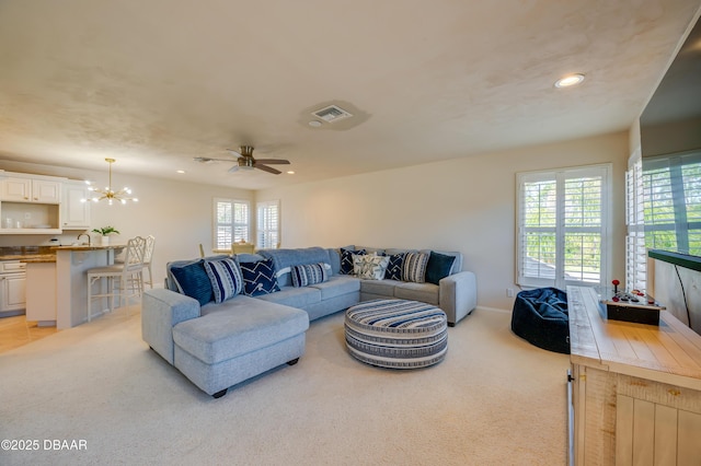 living room featuring recessed lighting, ceiling fan with notable chandelier, visible vents, and light carpet