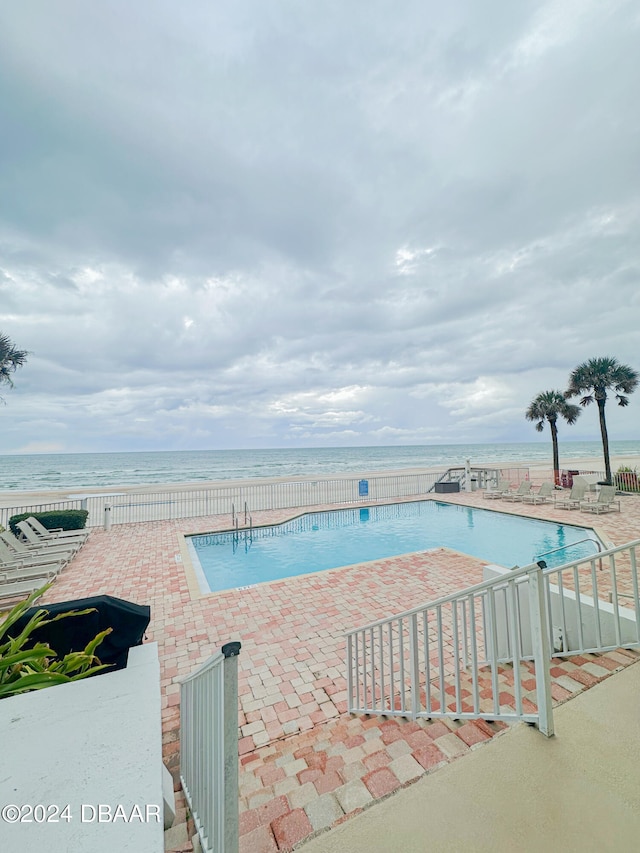 view of pool featuring a water view and a patio area