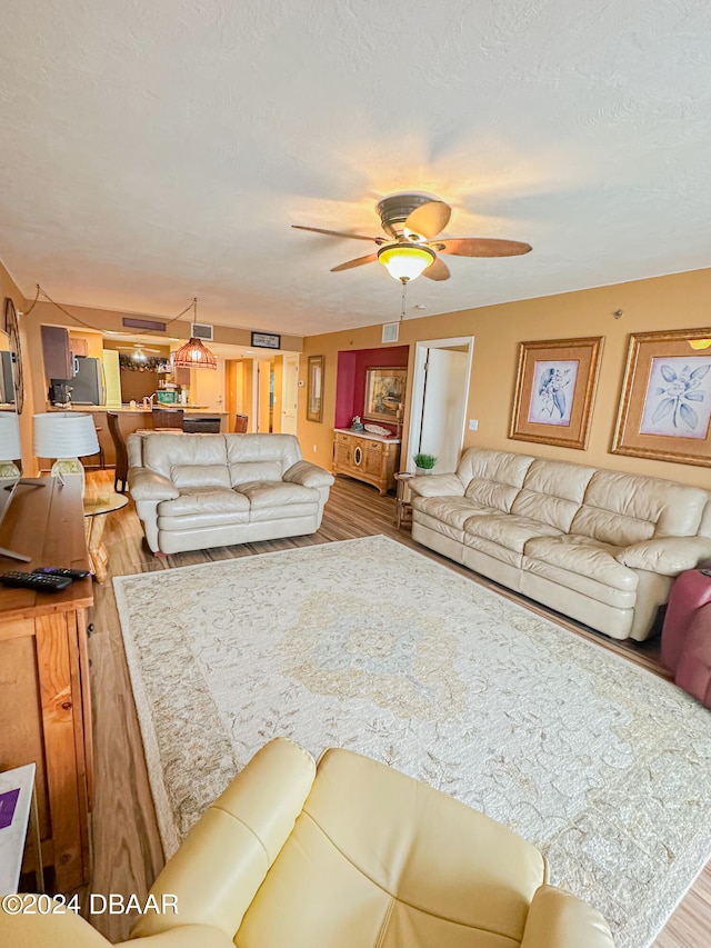 living room featuring a textured ceiling, hardwood / wood-style floors, and ceiling fan