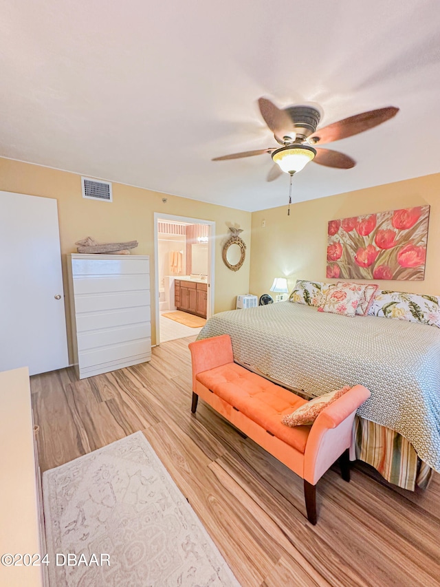 bedroom with ceiling fan, ensuite bath, and light wood-type flooring