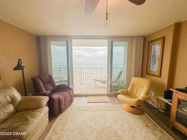 living room featuring a water view, a textured ceiling, hardwood / wood-style flooring, and ceiling fan