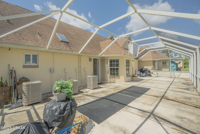 160 Big Ben Dr, Daytona Beach, FL 32117 - rear view of property with glass enclosure, a patio area, roof with shingles, central air condition unit, and stucco siding