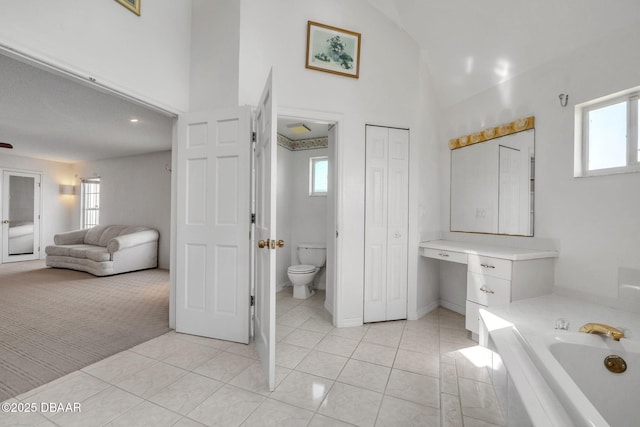 bathroom featuring tiled tub, tile patterned flooring, high vaulted ceiling, and toilet