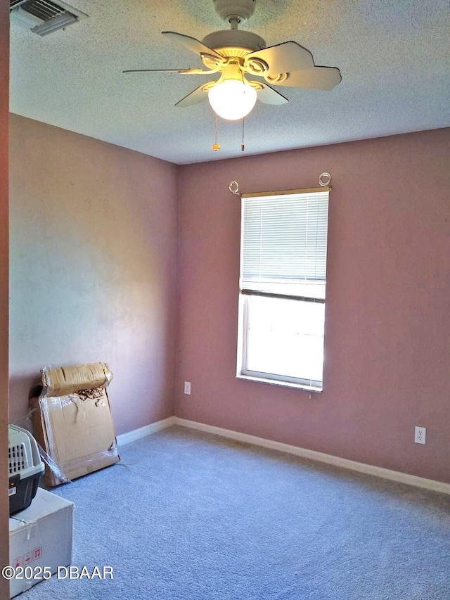 carpeted empty room with ceiling fan and a textured ceiling